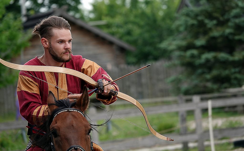 Horse rider shoots a bow at a target