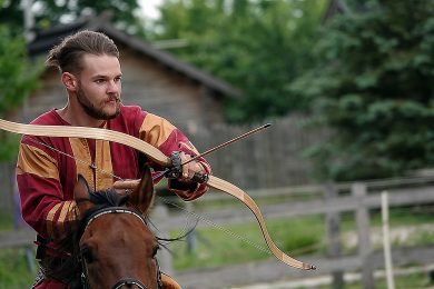 Horse rider shoots a bow at a target