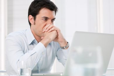 Pensive absorbed business man watching at computer laptop with worried expression