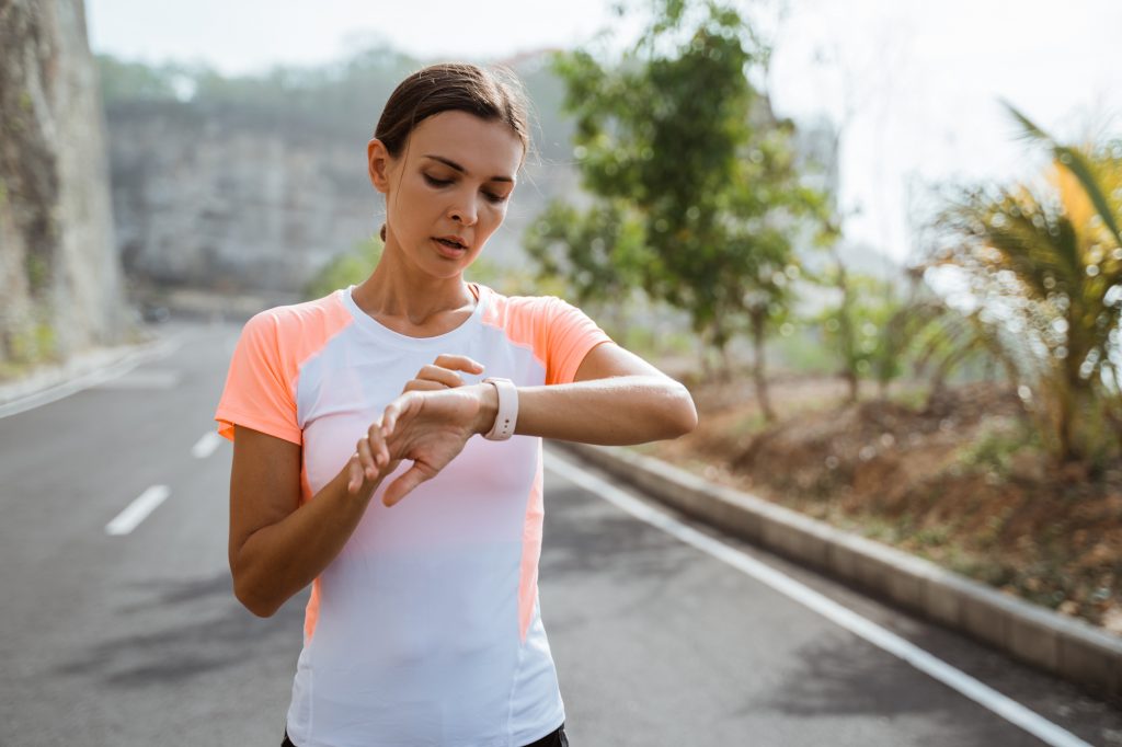Young athlete workout at park and adjusting smart watch. woman setting smartwatch before jogging