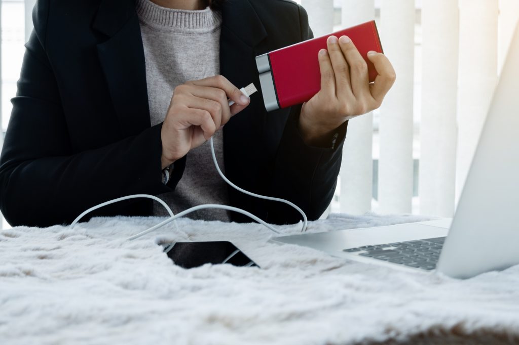 The hand of a young woman holding a smart phone and a modern Pow