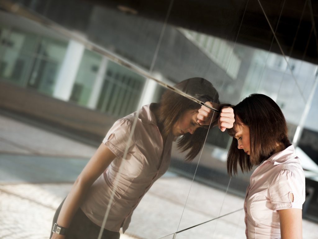 frustrated woman banging head against wall of office building