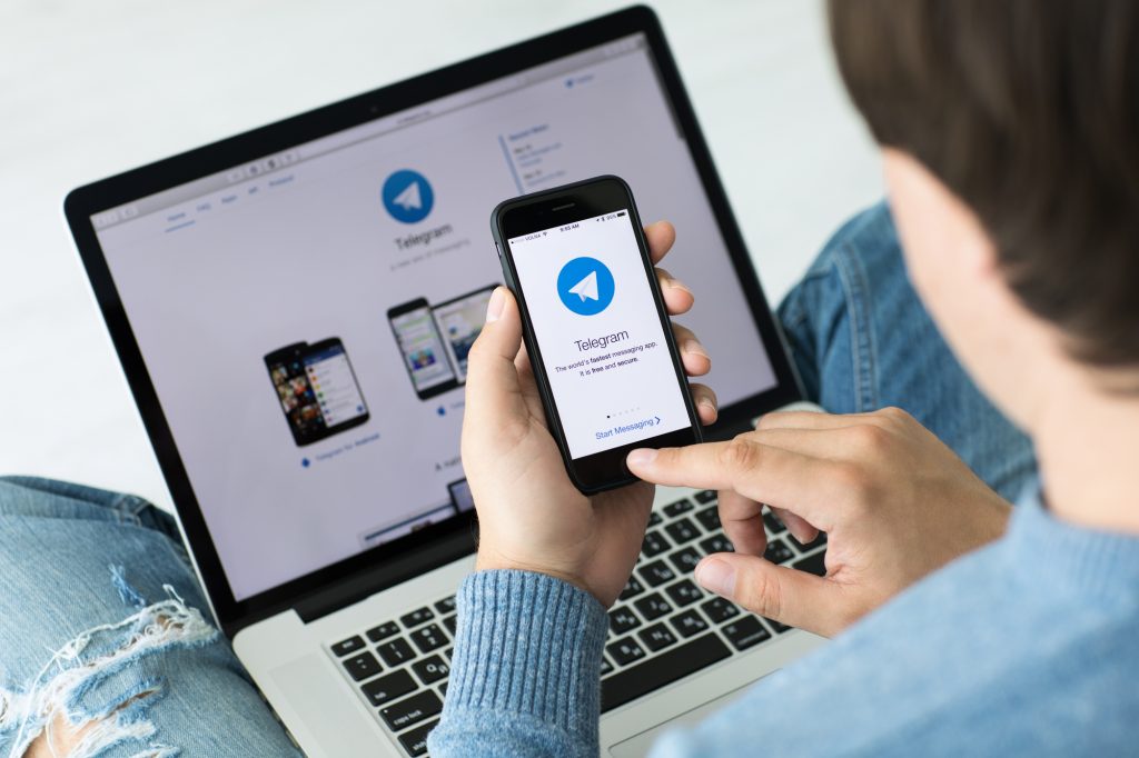 Man holding iPhone and MacBook Pro social networking service Tel