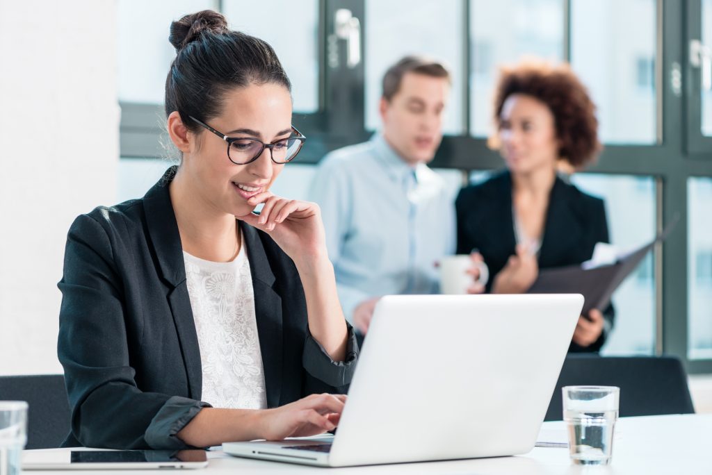Young woman smiling while using a laptop in the office