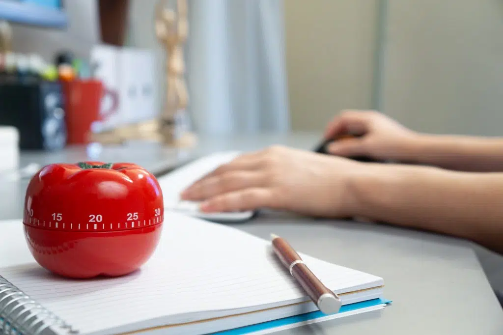 Selective focus shot of a kitchen timer in the form of a tomato on a notebook