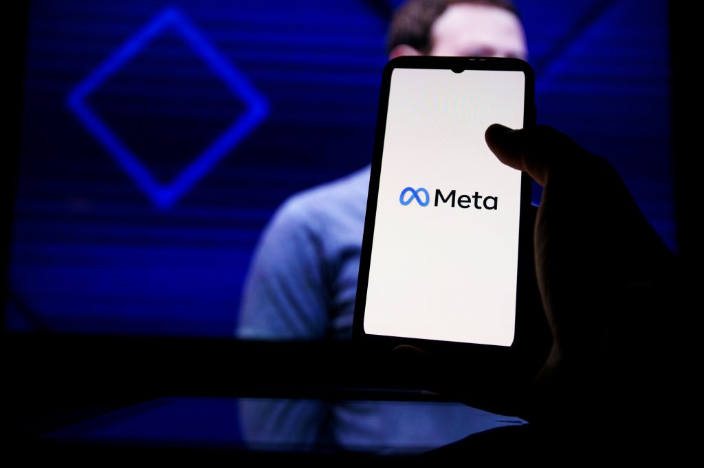 Meta logo on screen and Mark Zuckerberg is a Chief Executive Officer of Metaverse in background