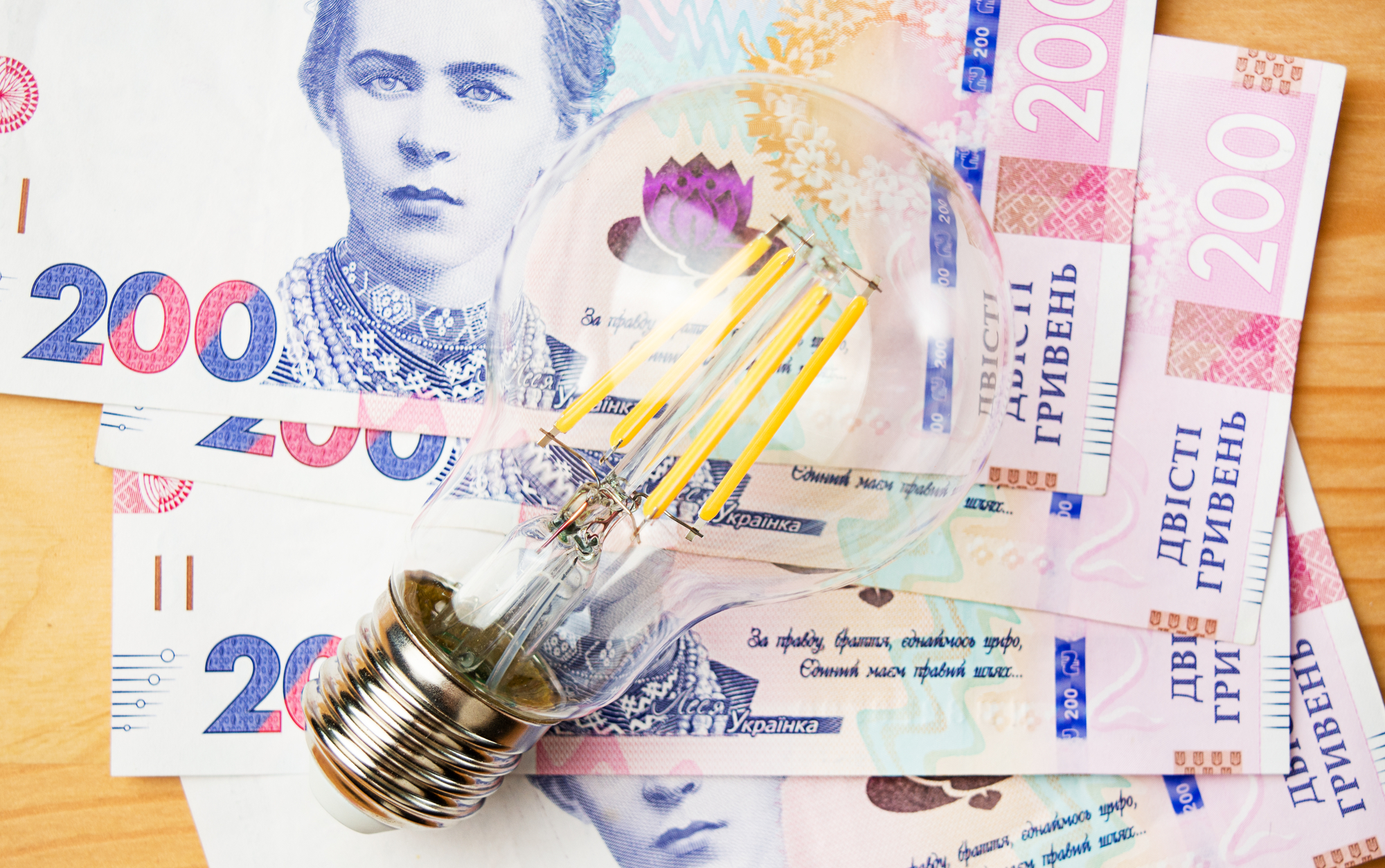 The concept of paying utility bills. The concept of electricity supply in Ukraine. A lamp and Ukrainian 200 hryvnia bills. Top view. Close-up.