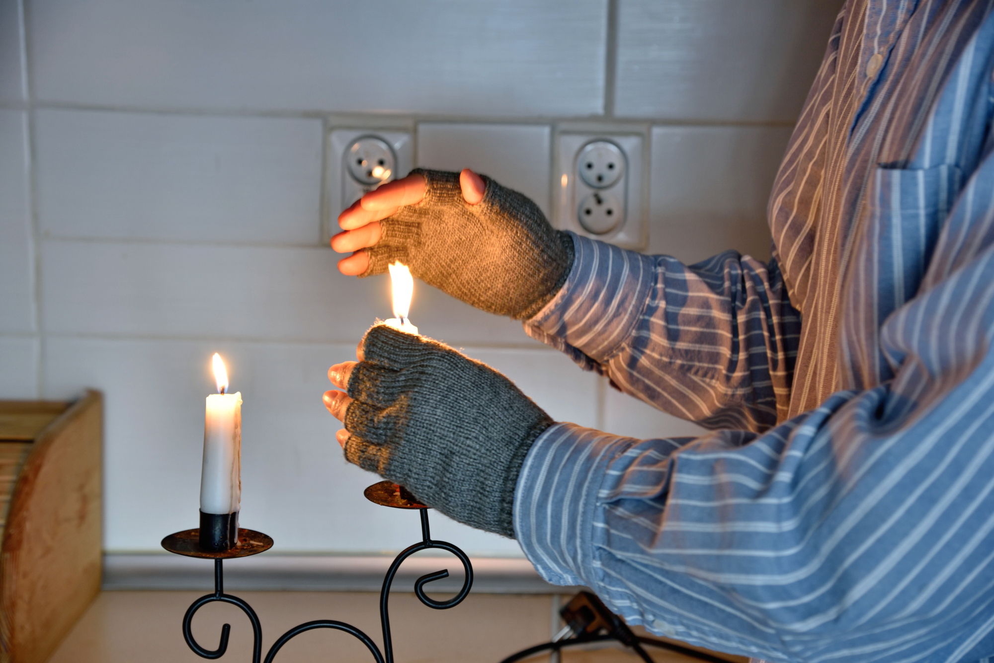Symbols of poverty: man at home without electricity, without heating. Using candles to warm up.