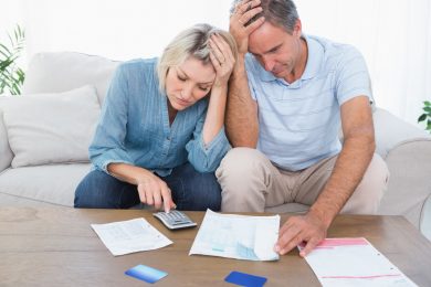 Worried couple going over finances at home in living room