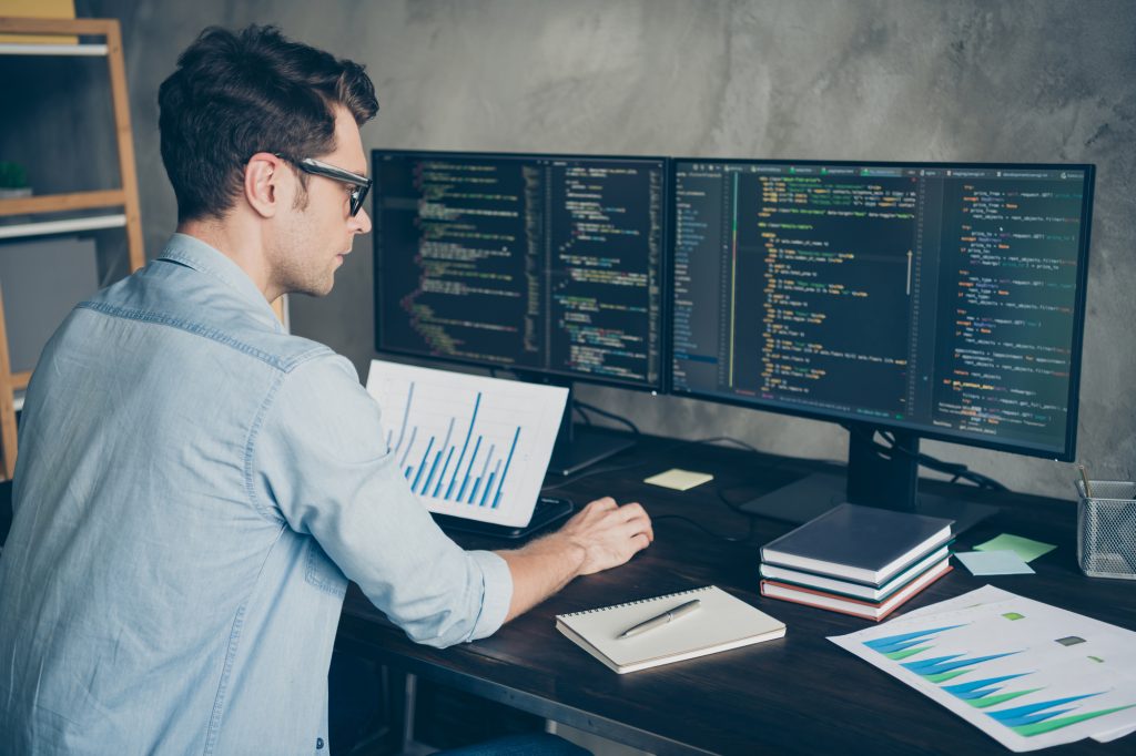 Profile side view portrait of his he nice attractive focused skilled guy geek coding programming writing database source at modern industrial interior loft concrete wall style work place station