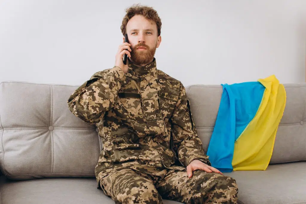 A Ukrainian soldier in military uniform is sitting on a sofa in