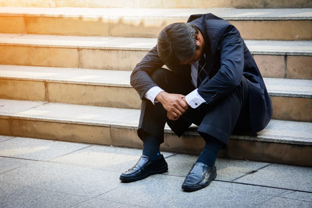 Stressed businessman sitting at stairway outdoor.Bankrupt businessman sitting outdoor.