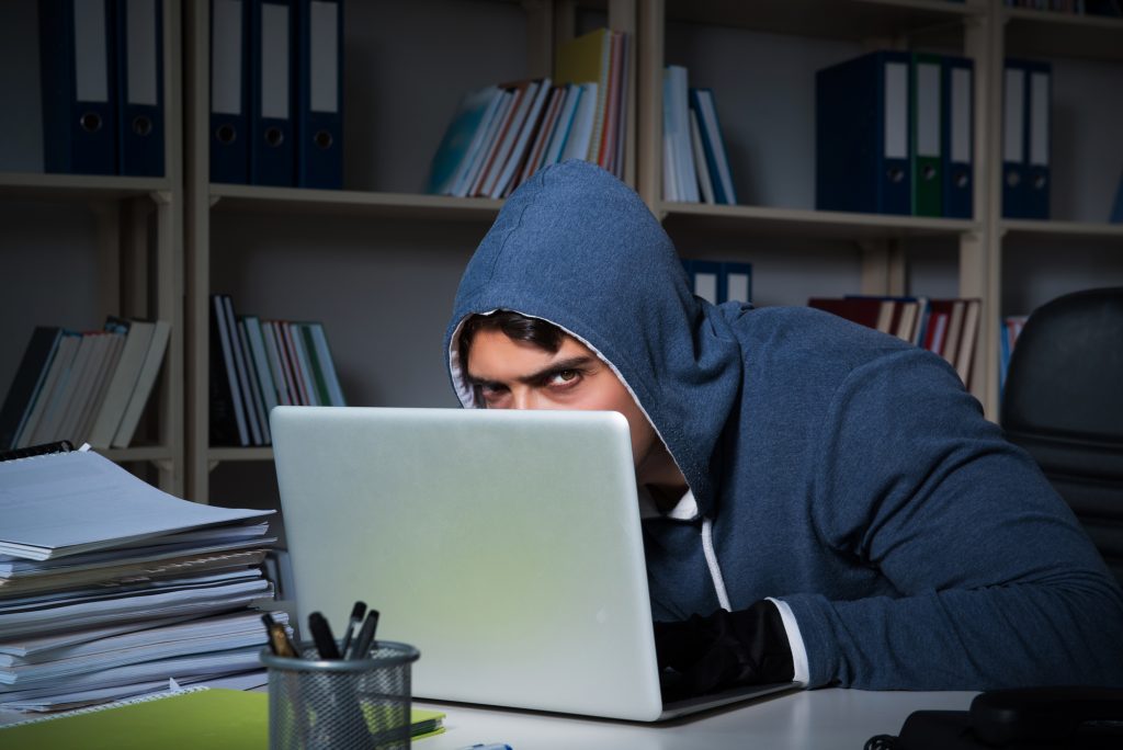 Young hacker hacking into computer at night