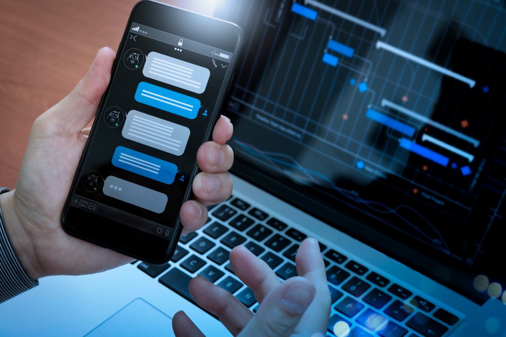 Chatbot conversation with smartphone screen app interface and artificial intelligence technology processing virtual assistant with customer support information, business hand holding mobile phone.