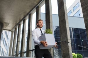 An unhappy young manager in a white shirt is fired from his job. A sad worker sits on the steps of a business center after layoffs. Crisis and unemployment