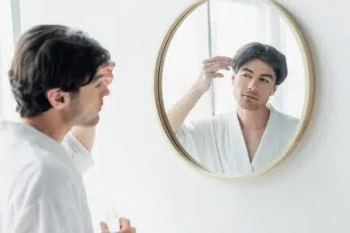 A young handsome man looks in the mirror