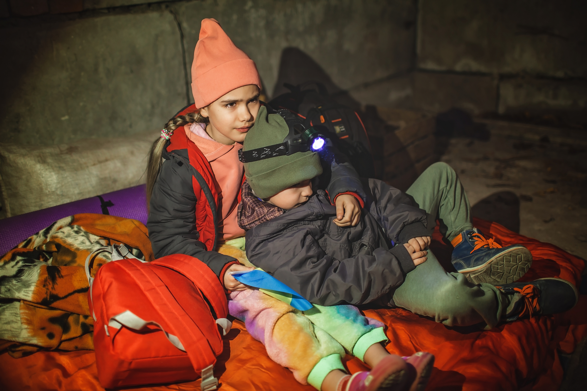 Kids with Ukrainian flag lay in bomb shelter and waits for end of airstrike of Russian invaders