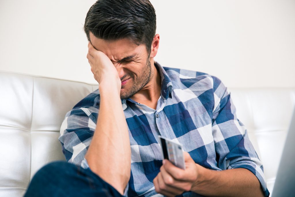 Sad man holding bank card