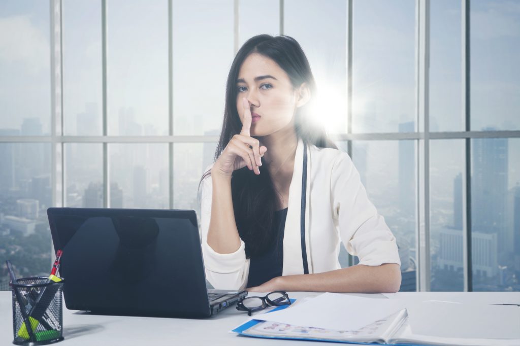 Asian businesswoman gesturing silence sign