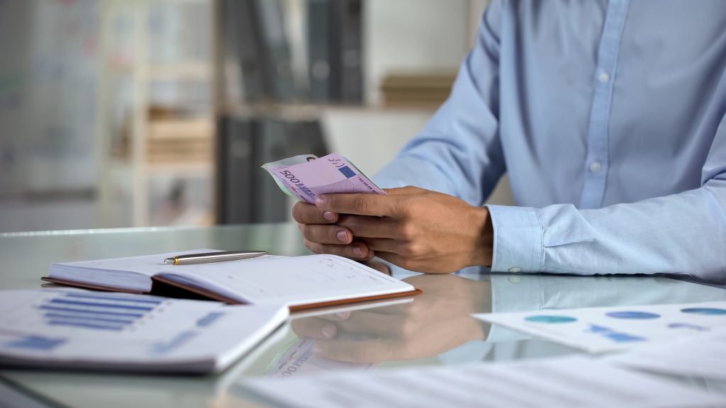 Man planning budget, counting euro in office, small business income distribution