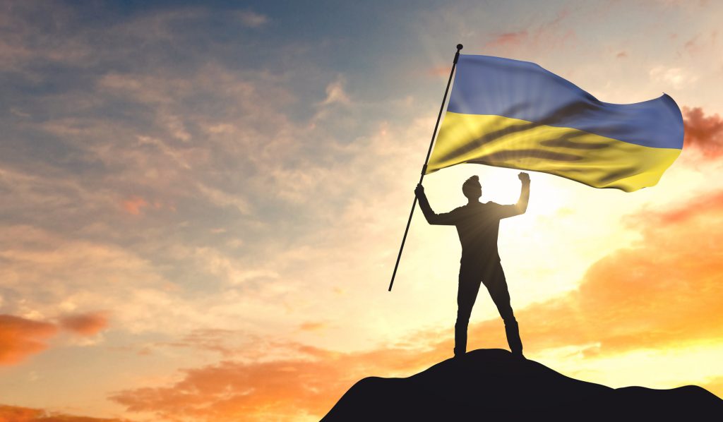 Ukraine flag being waved by a man celebrating success at the top