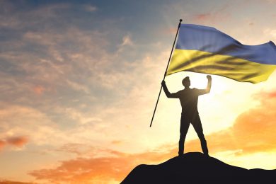 Ukraine flag being waved by a man celebrating success at the top
