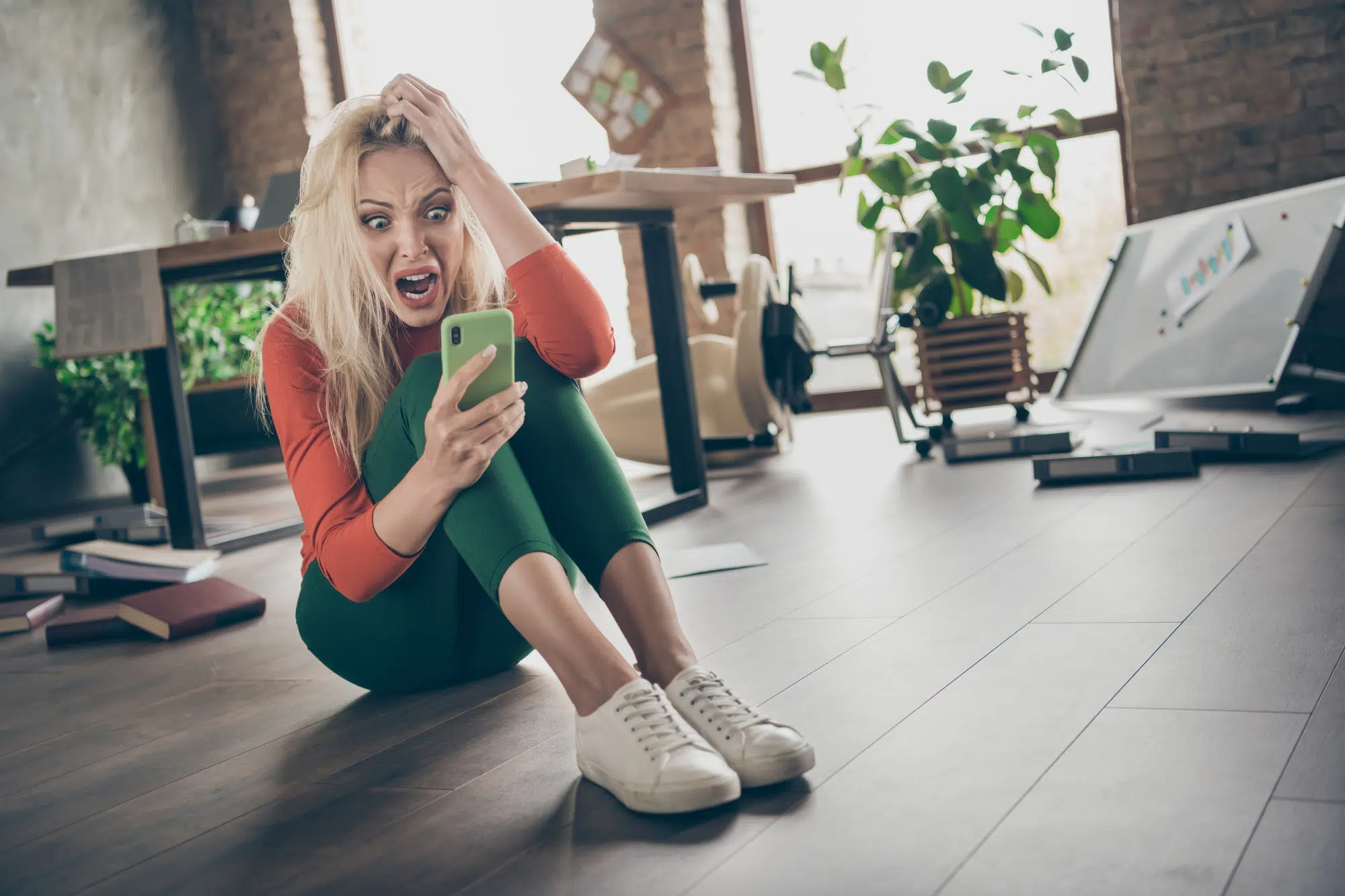Full size photo of overwhelmed crazy mad woman start-up representative agent sit floor use smartphone get dismissal notification yell panic touch blonde hair in messy office loft workplace