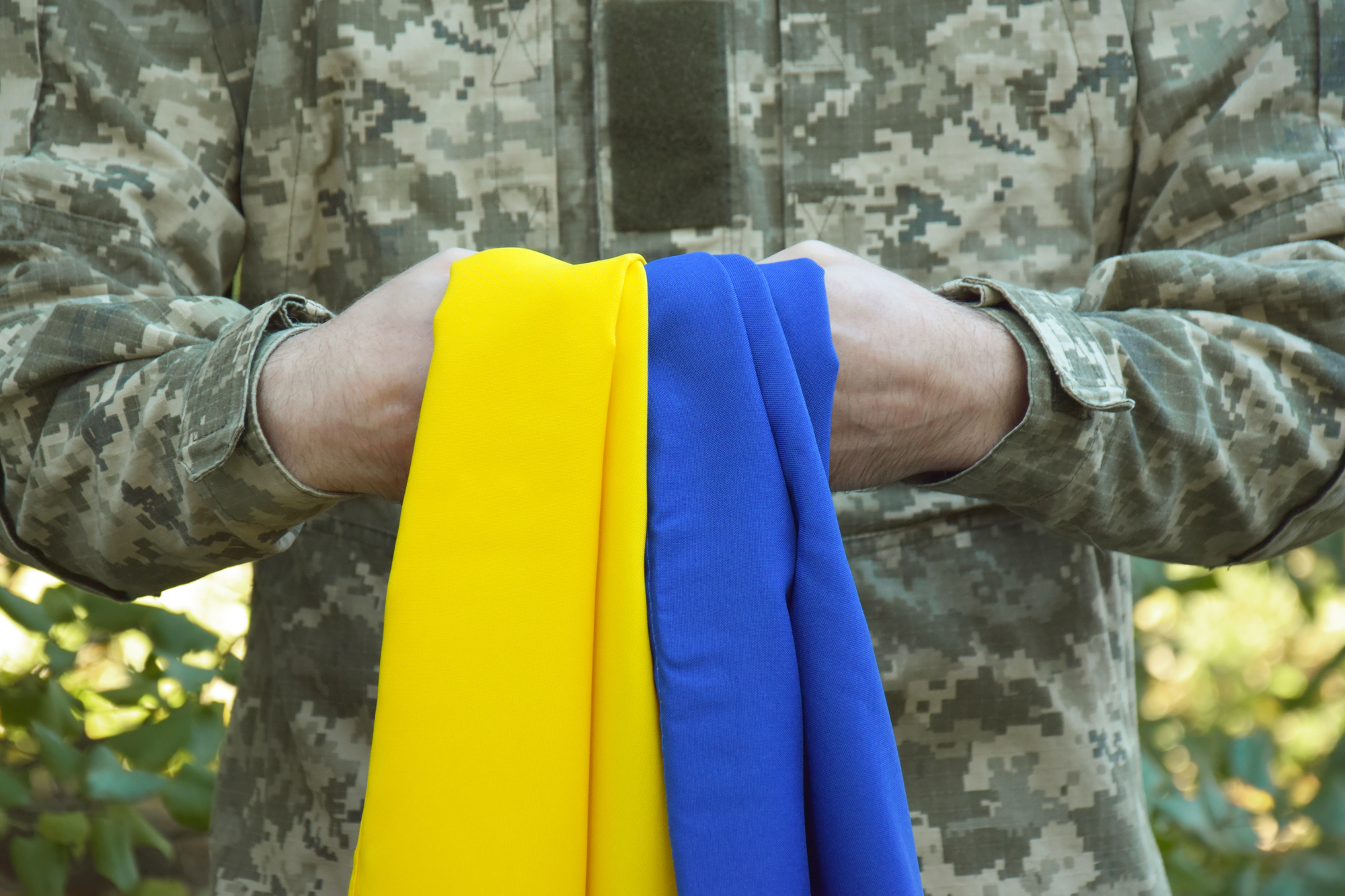 A Ukrainian military man holds the national flag in his hands as a symbol of strong