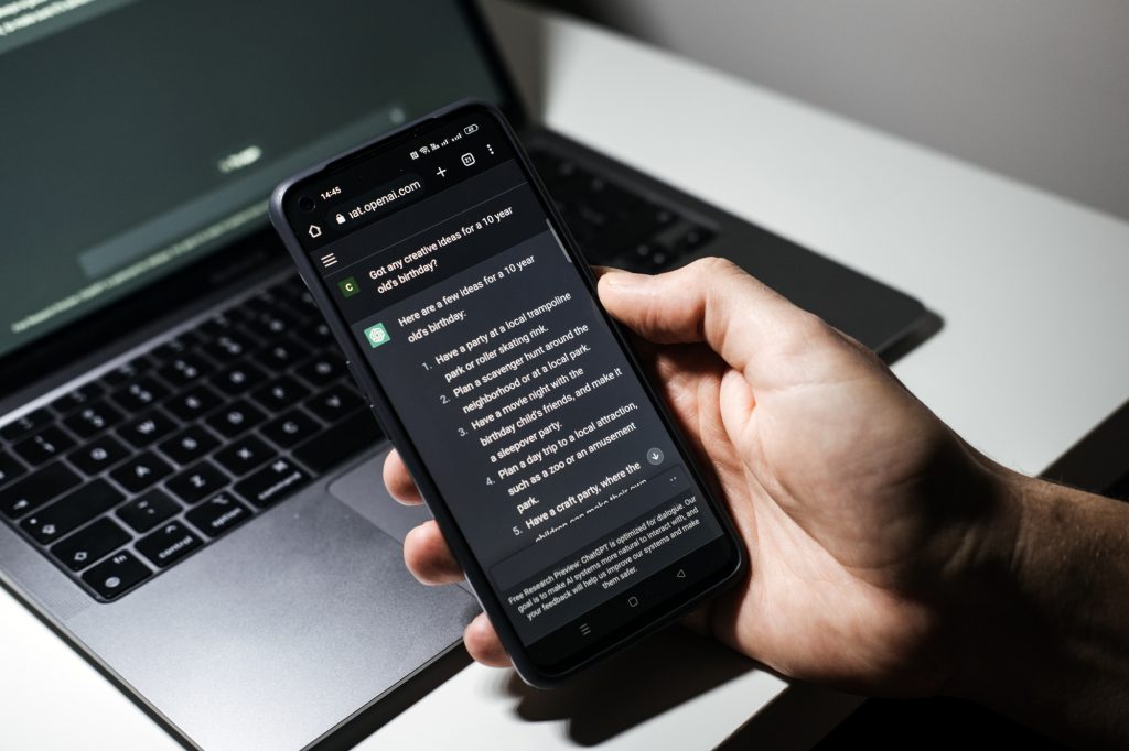 Screen with ChatGPT chat with AI or artificial intelligence. Man search for information using artificial intelligence chatbot developed by OpenAI. Warsaw, Poland - December 02, 2022