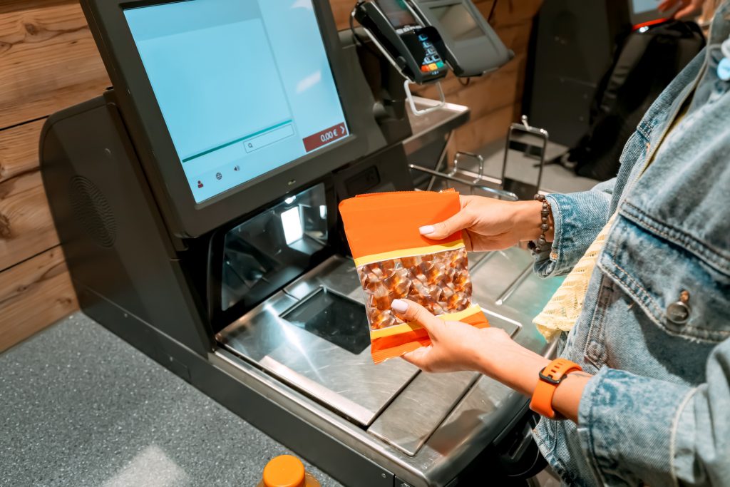 A girl customer scanns and pays for goods from a supermarket in an automated self-service checkout terminal