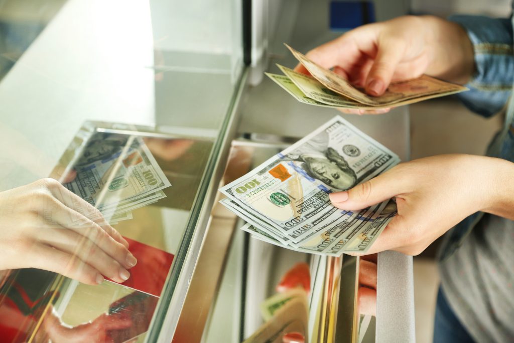 Female hand with money in cash department window. Currency exchange concept