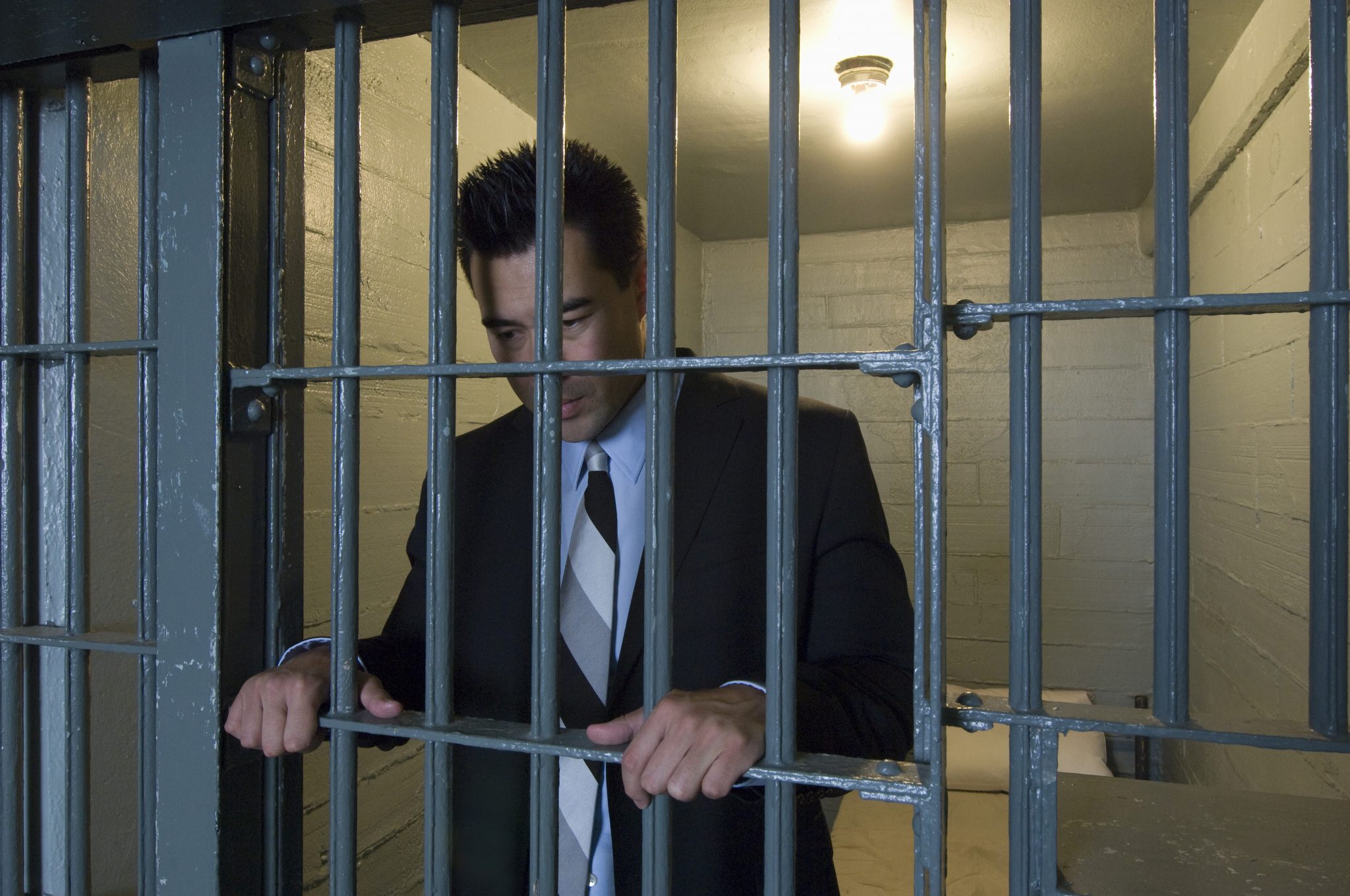 A middle aged business man standing behind bars