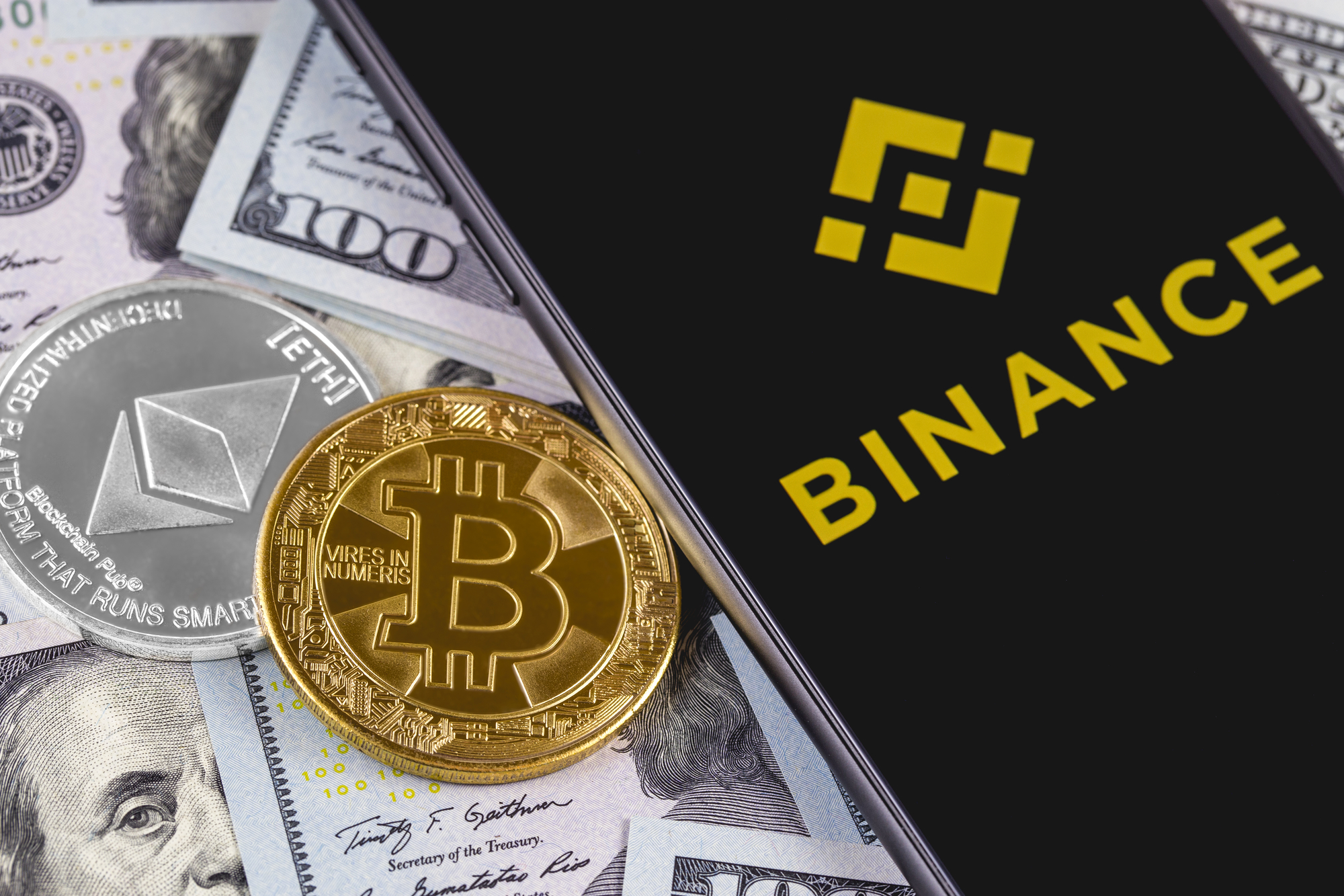 Apple iPhone and Binance logo and bitcoin, ethereum and dollars. Binance is a cryptocurrency exchange. Ekaterinburg, Russia - September 19, 2018