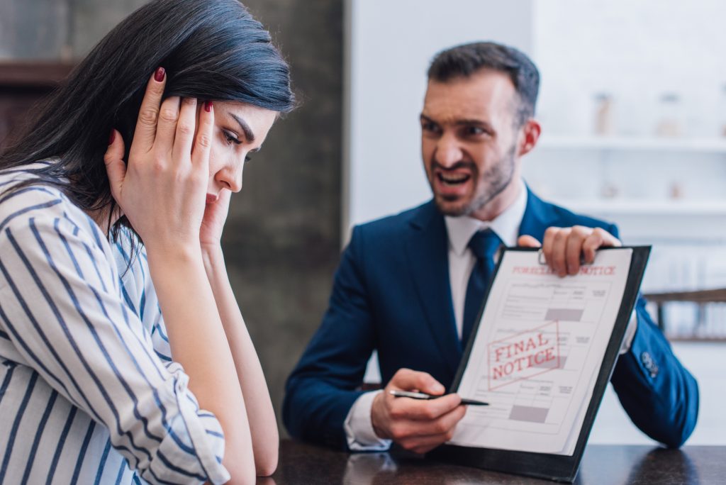 An upset young woman receives a final warning from the bank about an overdue loan