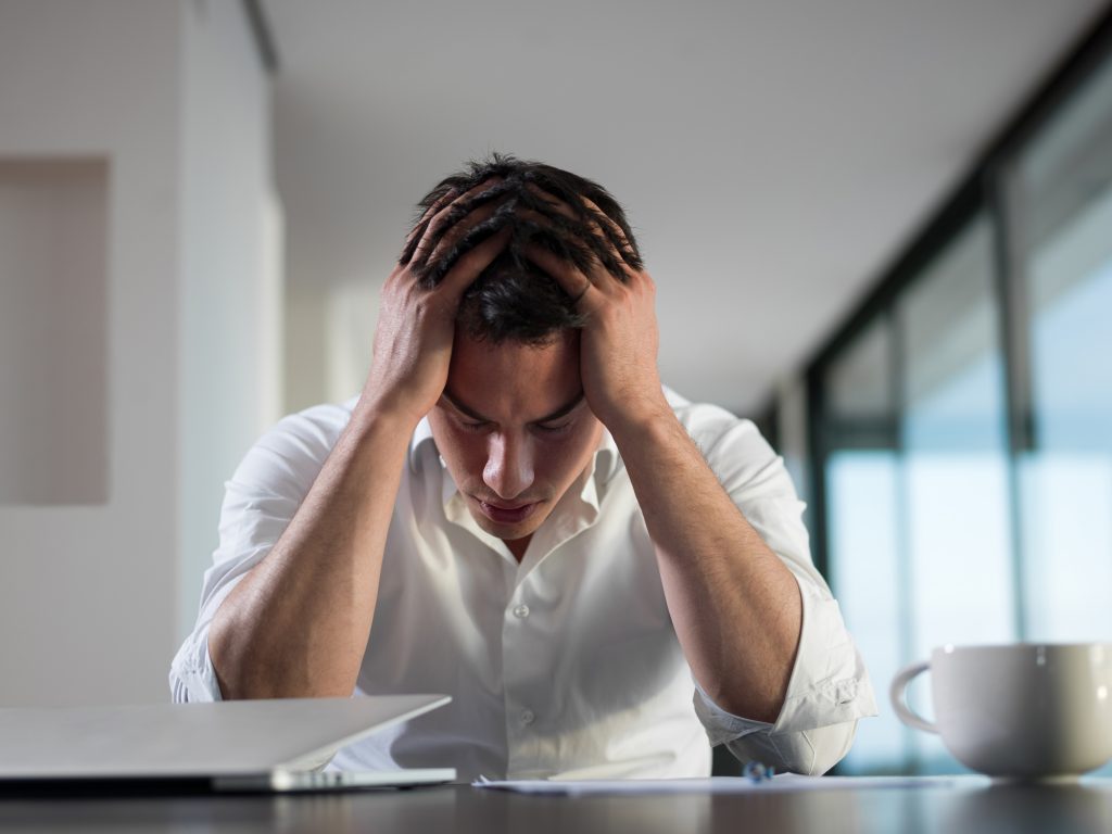 frustrated young business man working on laptop computer at home