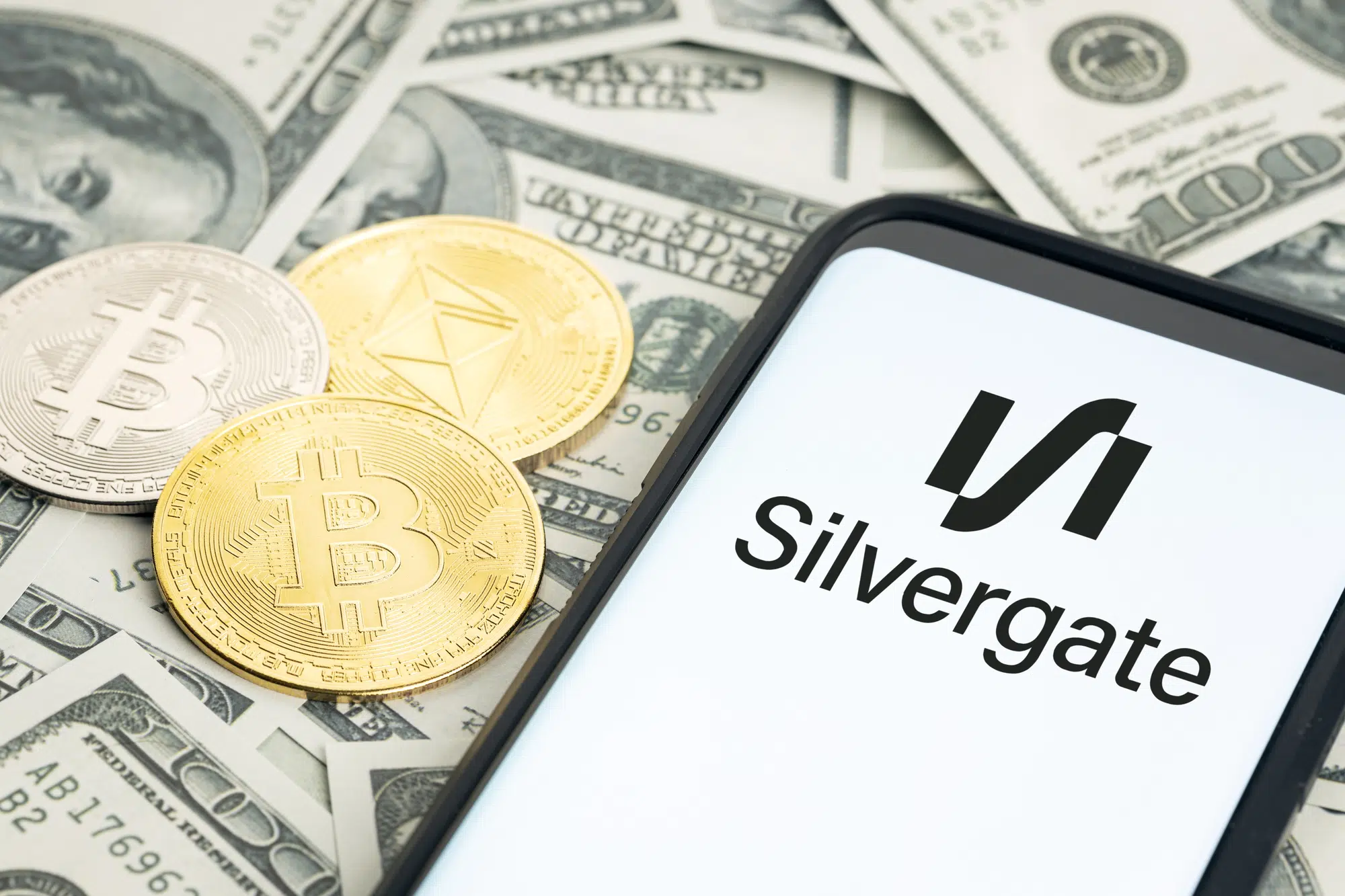 Galicia, Spain; january 28, 2022: Silvergate financial services company logo on Smartphone screen, dollar banknotes and crypto coins on table