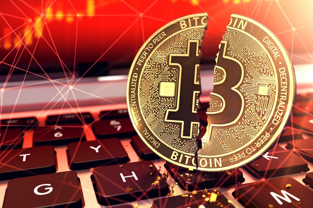 Bitcoin split in two pieces on keyboard. Frauds and ransoms committed with cryptocurrencies concept. 3D rendering