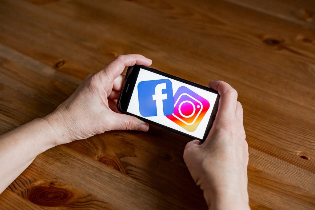 Facebook and instagram logo sign application screen on mobile phone online retail service, hands on, facebook and instagram sign