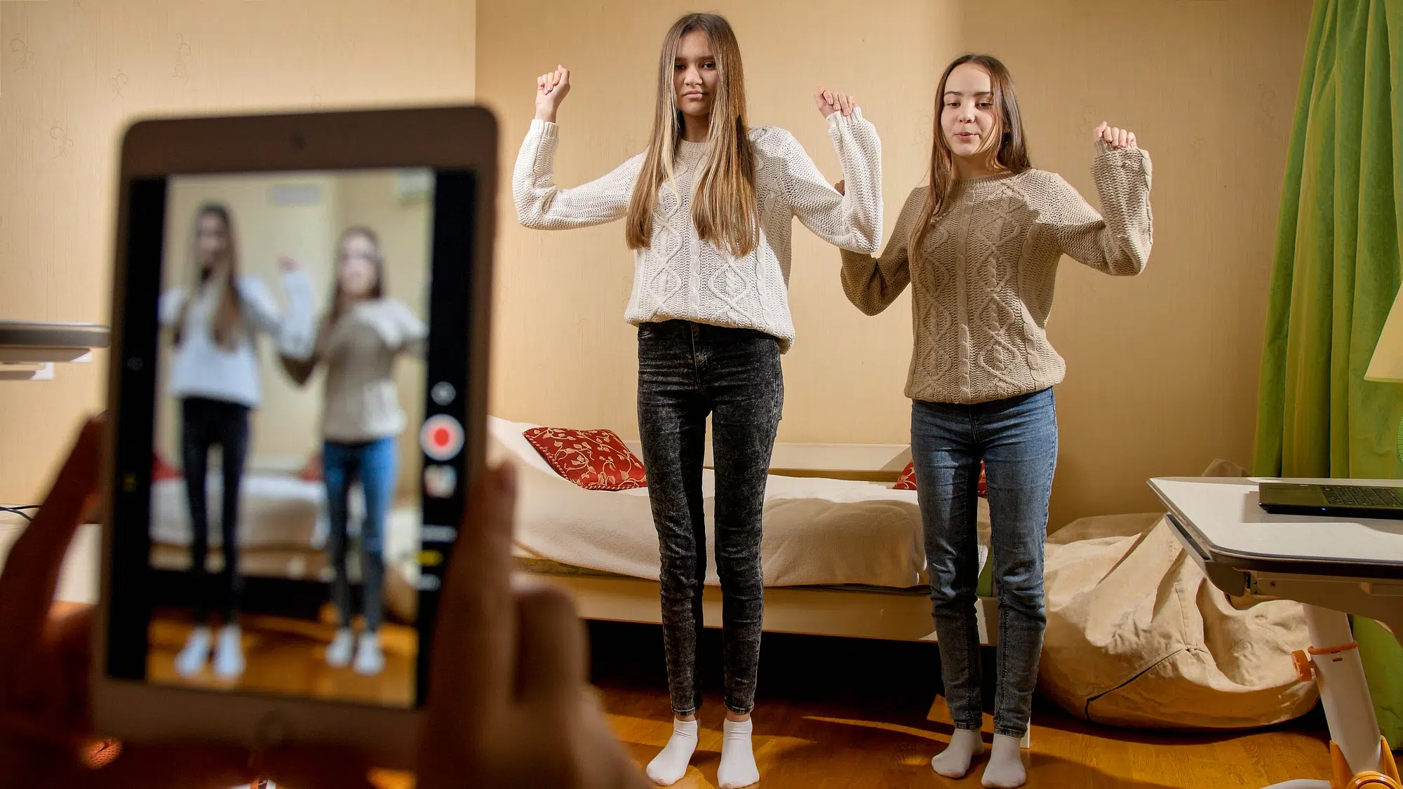 REcording video on smartphone of two teenage girls dancing for posting in internet. Modern communication, social media and gadgets.