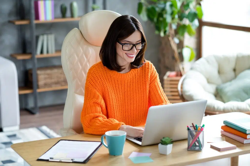 Photo of positive happy lady editor wear sweater writing news information read cv chatting video call conference macbook indoors.