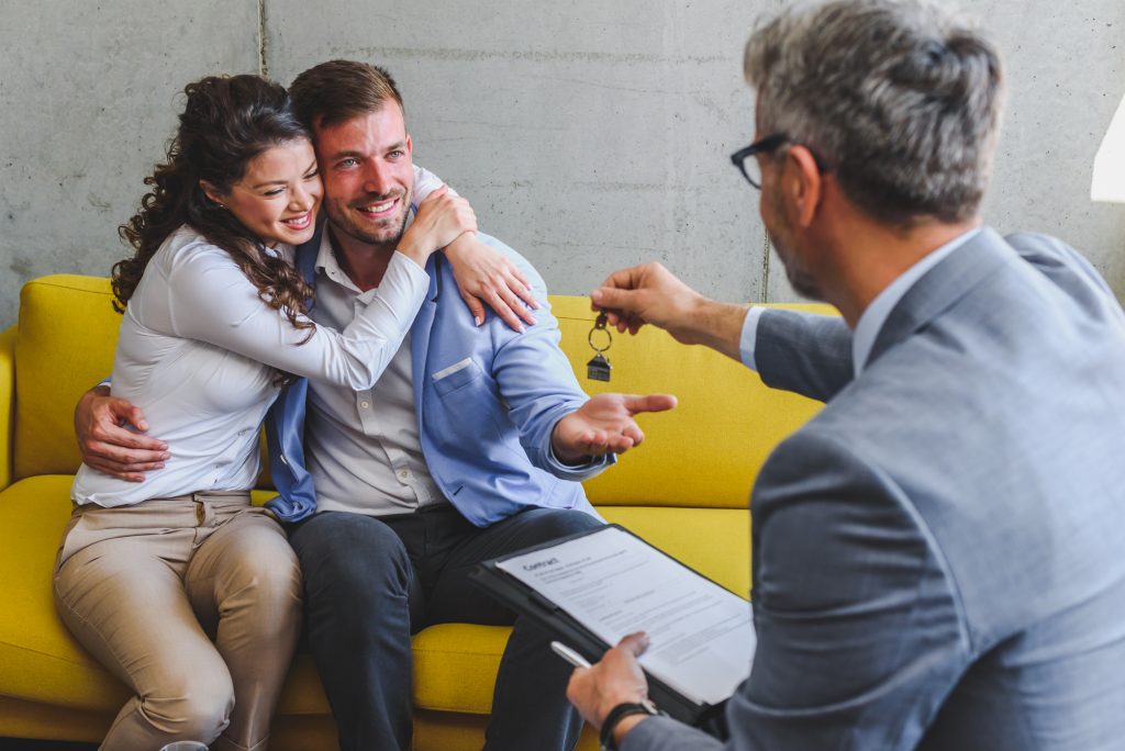 A married couple has signed an agreement to buy a home and is getting the keys from the realtor
