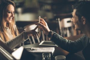 Young fashionable couple at the bar using a mobile touch screen phone