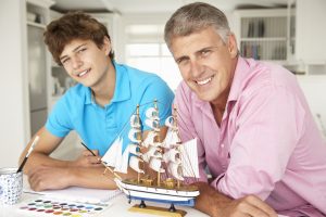 Father and teenage son model making and painting