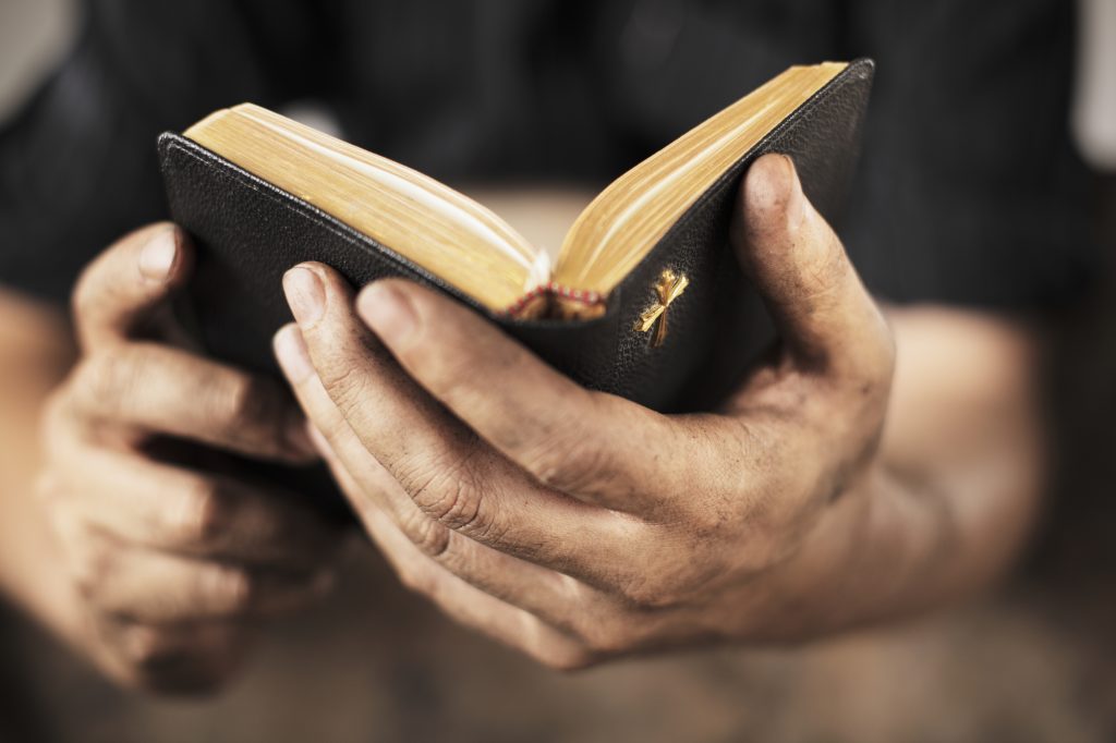 Dirty hands holding an old bible. Very short depth-of-field