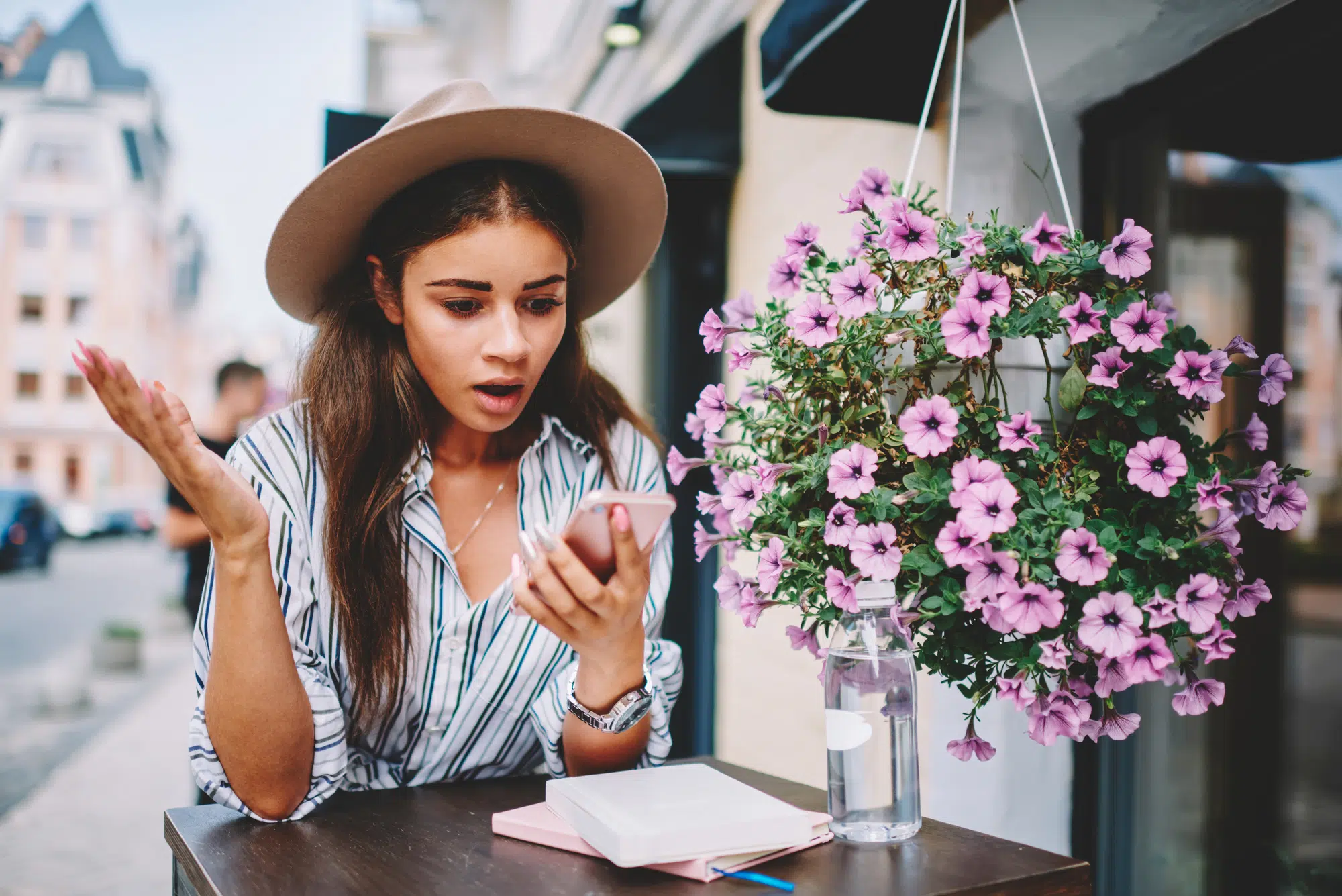 Emotional hipster girl in trendy hat confused with bad internet connection on cellular in cafe on street,young woman wondering while checking notification from banking service via smartphone