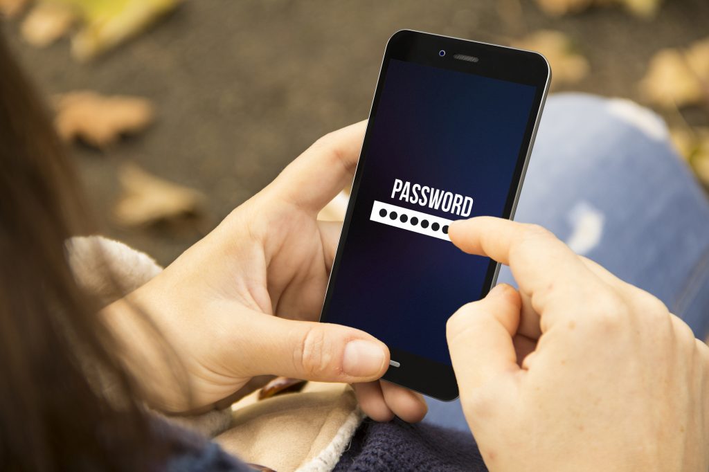 mobile security concept: young woman entering password on a 3d generated phone at the park