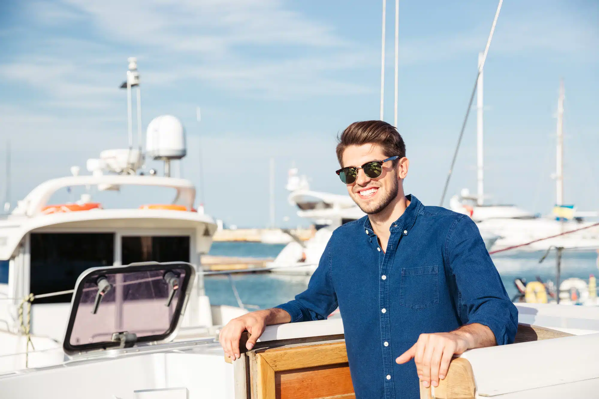 Bearded man wearing sunglasses and standing on a yacht