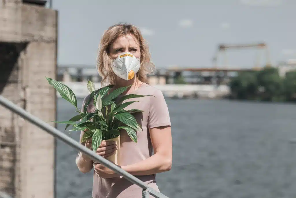 Polluted air, a woman in a respirator holding a vase, photo concept