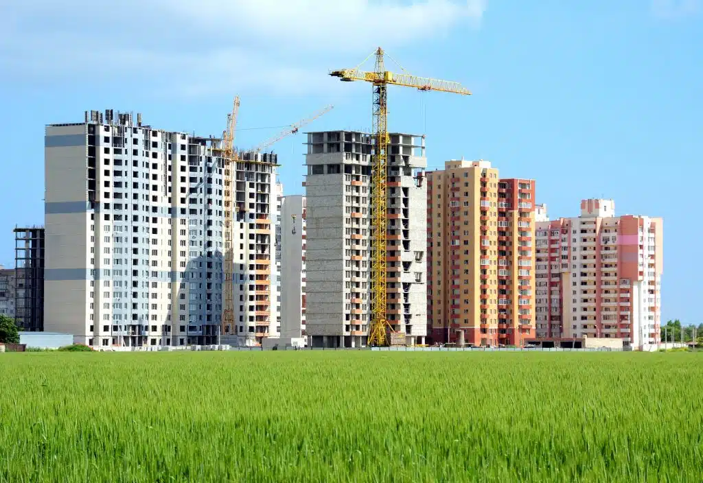 Residential buildings, some of them under construction, with beautiful green field foreground