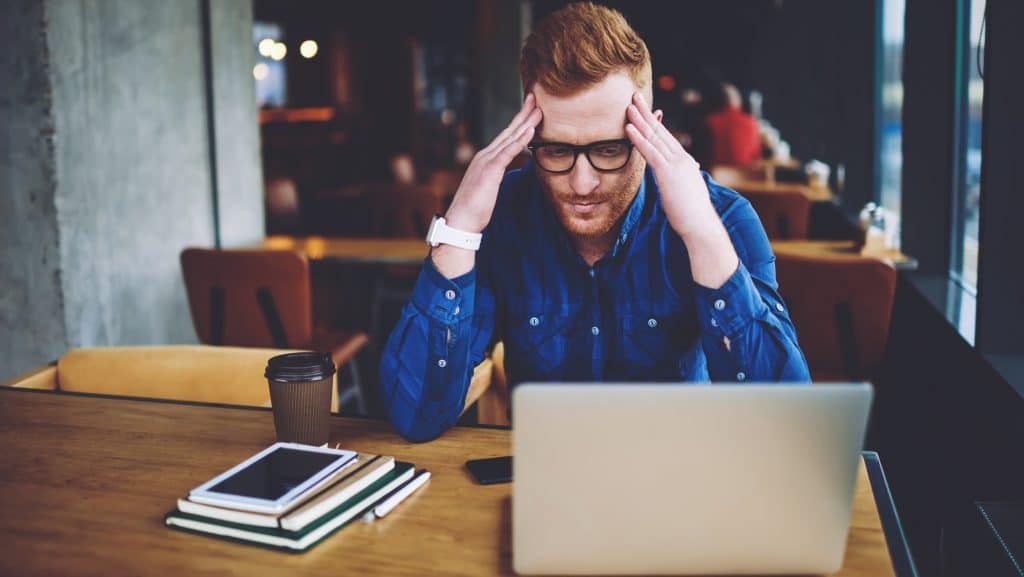 Disappointed caucasian male freelancer received email with bad news from work feeling unhappy from deadline in coworking space, puzzled man thinking about ideas for solving problem with antivirus app